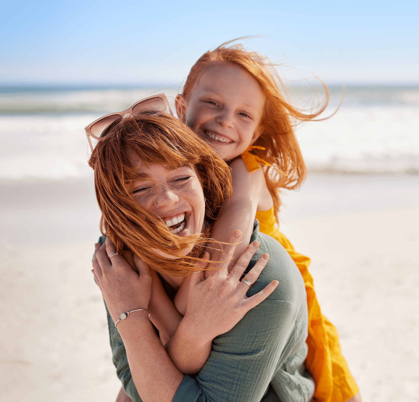 Mother and daughter smiling at beach.